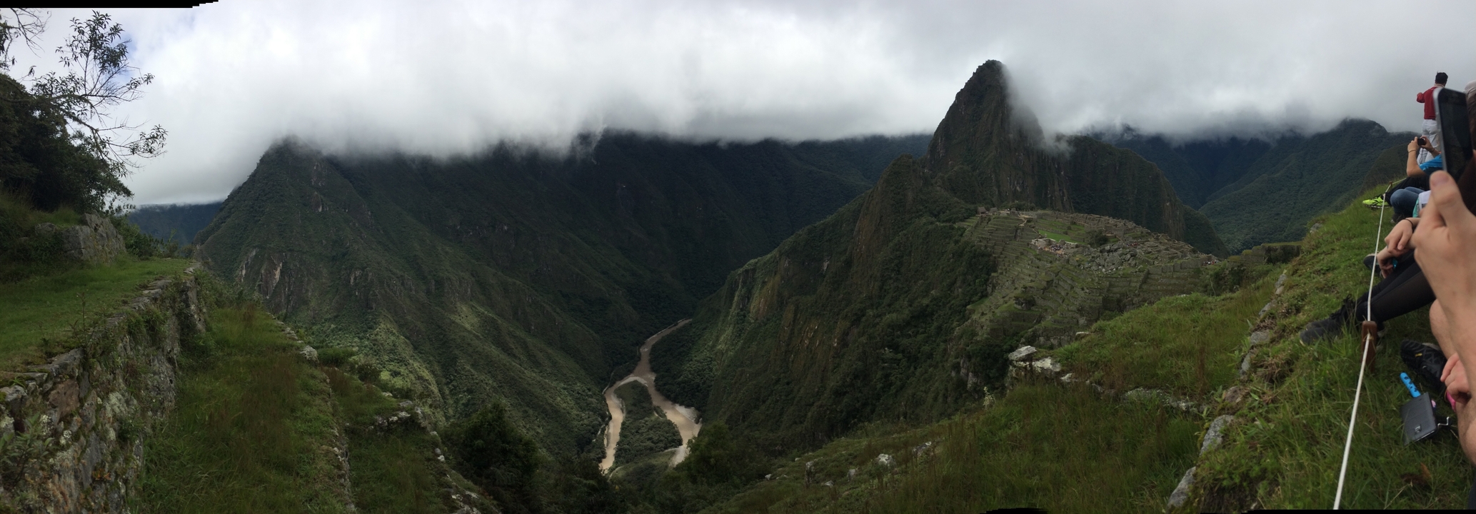 Wide panoramic view of Machu Picchu valley with winding river under low clouds
