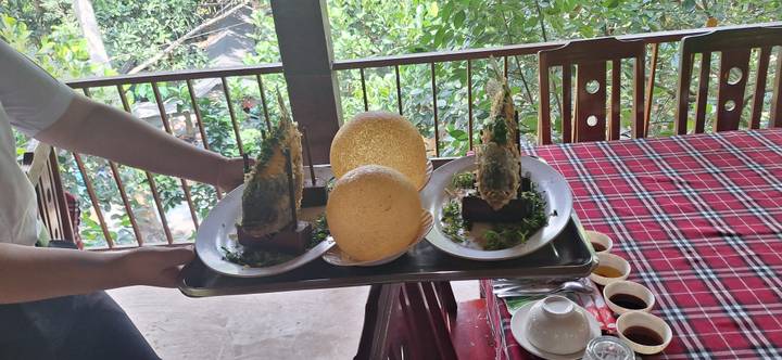 Tafel met gerechten van traditioneel Vietnamees eten, geserveerd in een tropische omgeving.