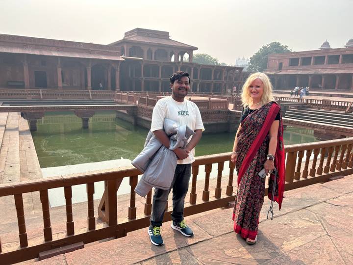 Two people posing by a water feature in a historic site.