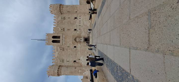 Historic fort entrance with people walking on a paved path.