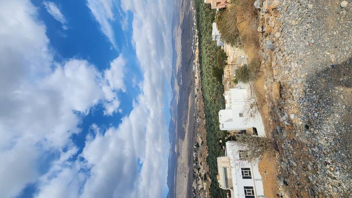 Desert village with white houses, mountains in background.