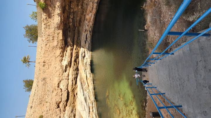 Boundary of a water-filled sinkhole, with people descending steps.