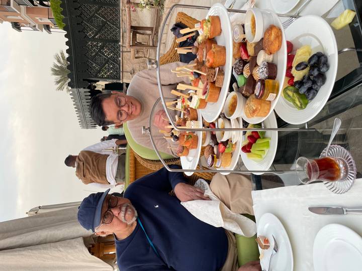 People enjoying high tea with a variety of snacks.