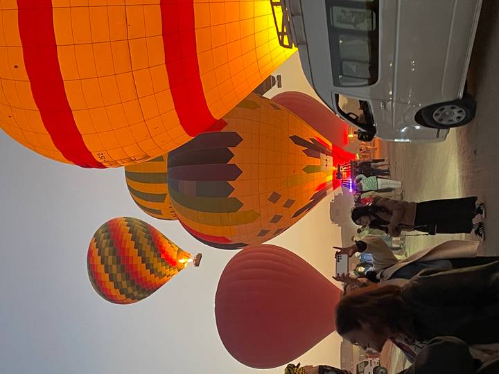 Colorful hot air balloons lifting off with people below.