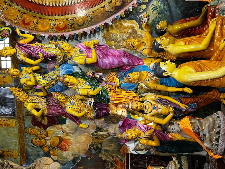 Market scene with people purchasing fruit under a canopy of trees.