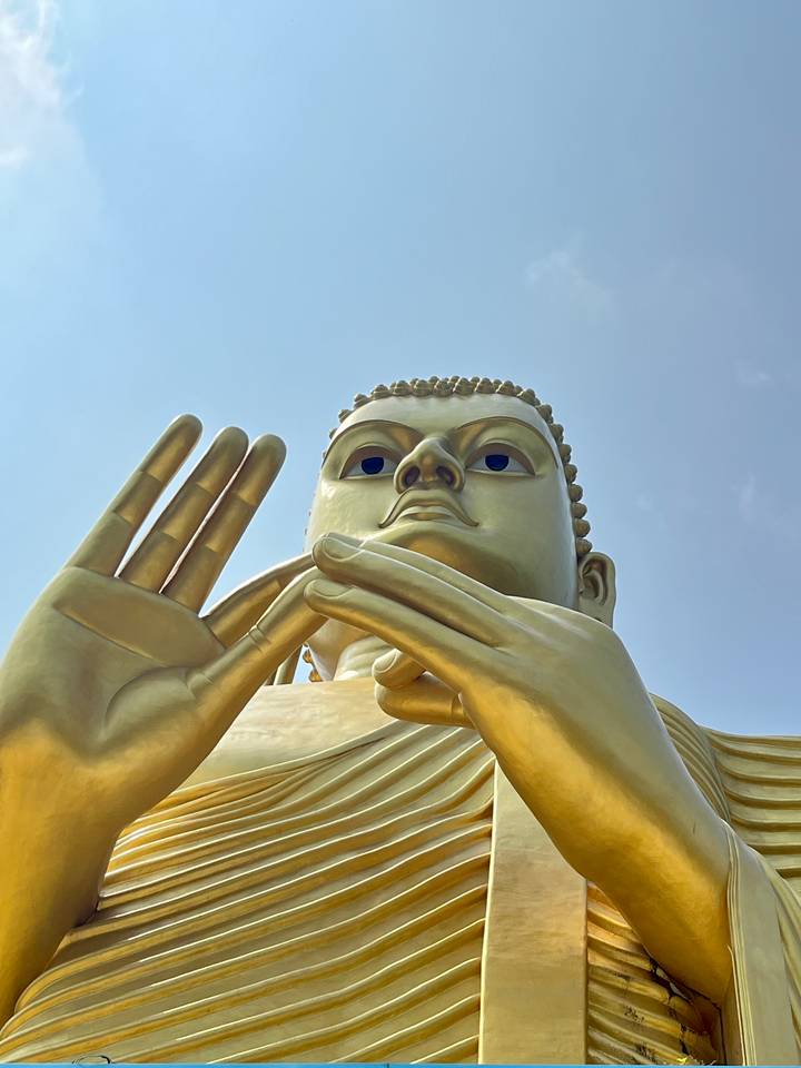 Golden Buddha statue against a clear sky.
