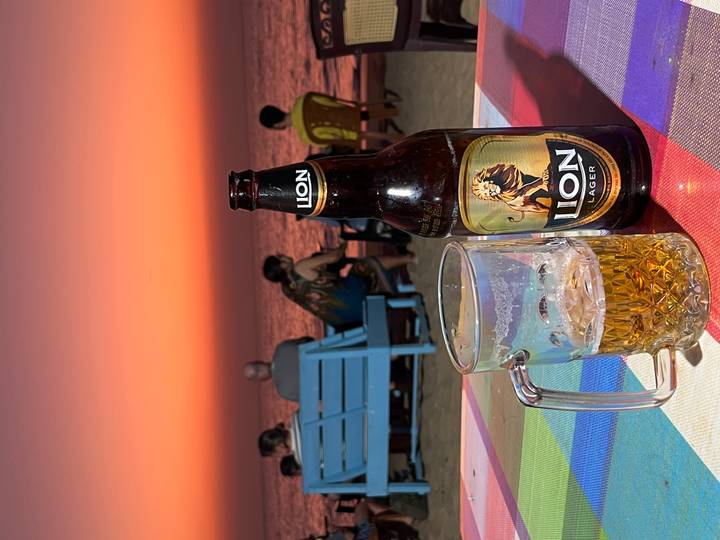 Group enjoying drinks at the beach with a colorful sunset in the background.