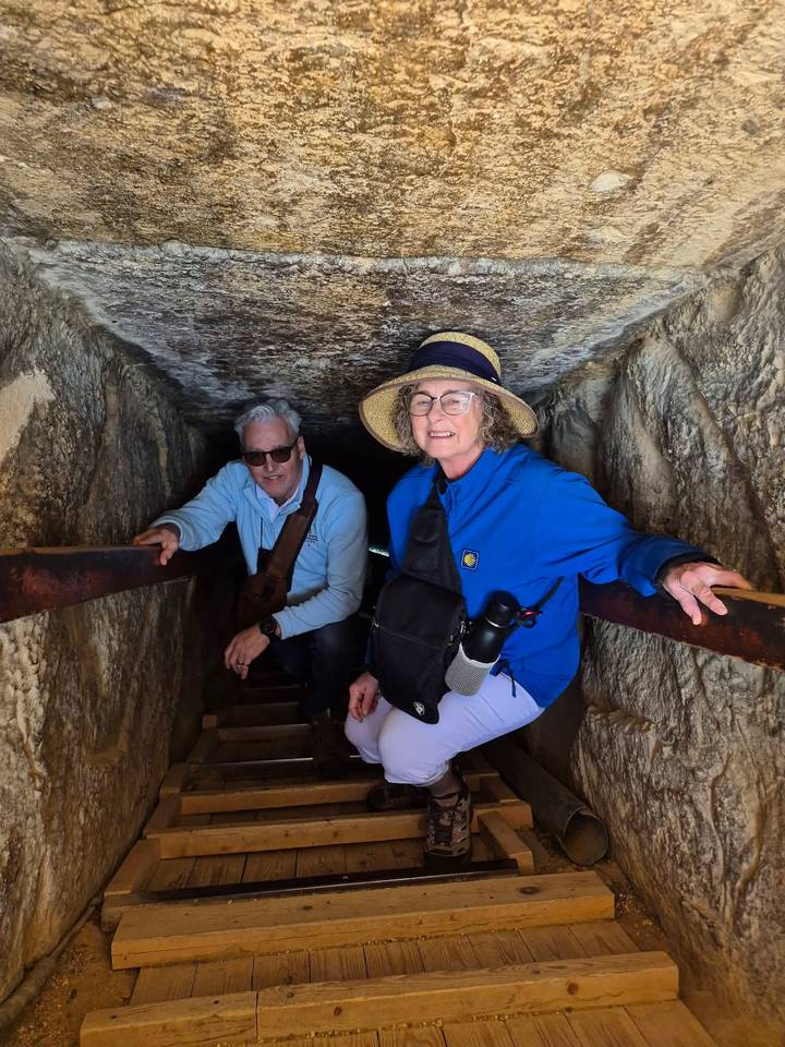 Two people exploring inside a narrow stone passage.