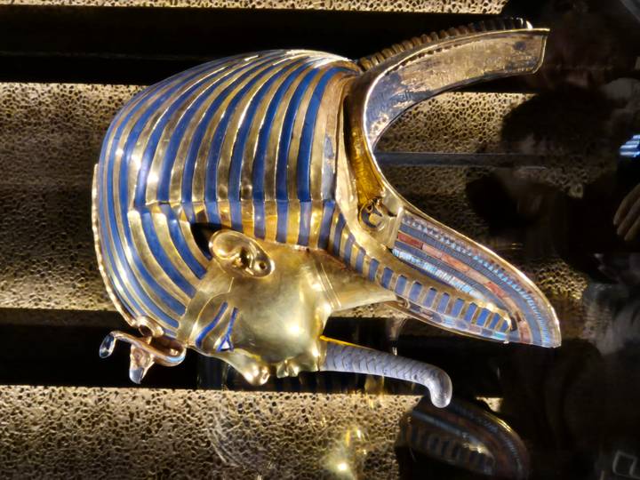 Golden mask of Tutankhamun in a museum display.