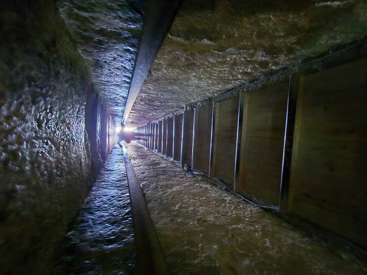 Shadowy figure in a long narrow stone passageway.
