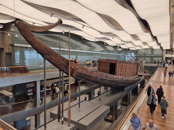 Large ancient wooden boat displayed in a modern museum.