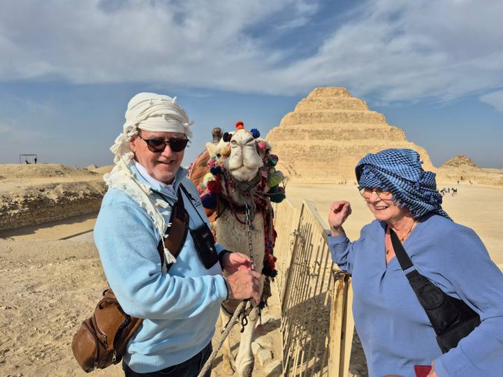 Couple with a camel standing in front of a pyramid.