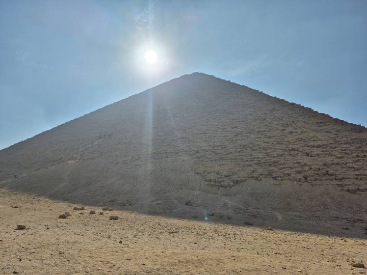 Sun shining over a large pyramid.
