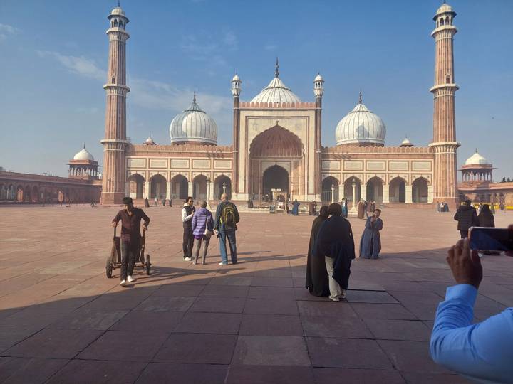 Large mosque courtyard with people walking.
