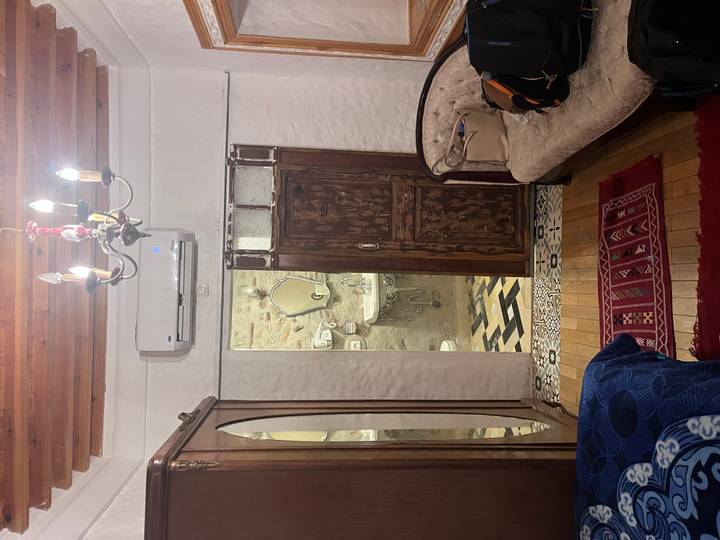 Interior of a traditional Moroccan room with wooden furniture and a view into a bathroom.