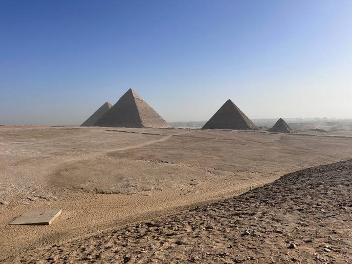 Pyramids of Giza under a clear sky in a sandy landscape.