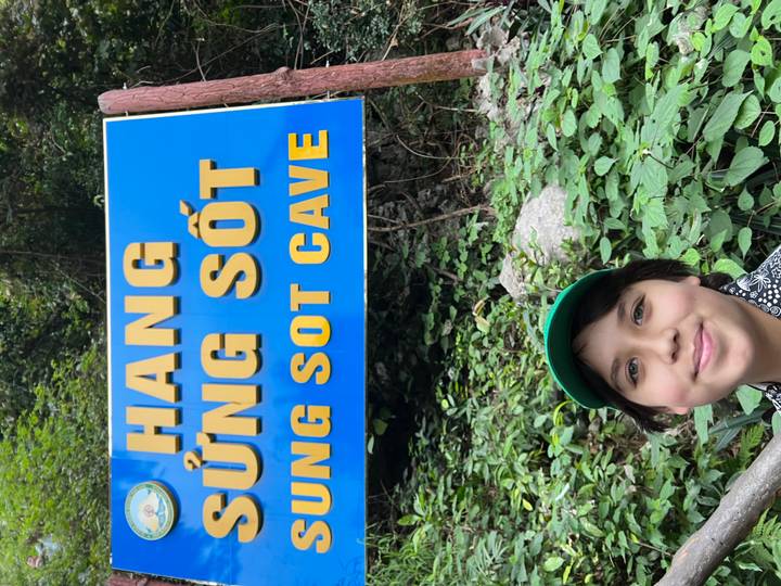 Young person posing next to a sign for Sung Sot Cave.
