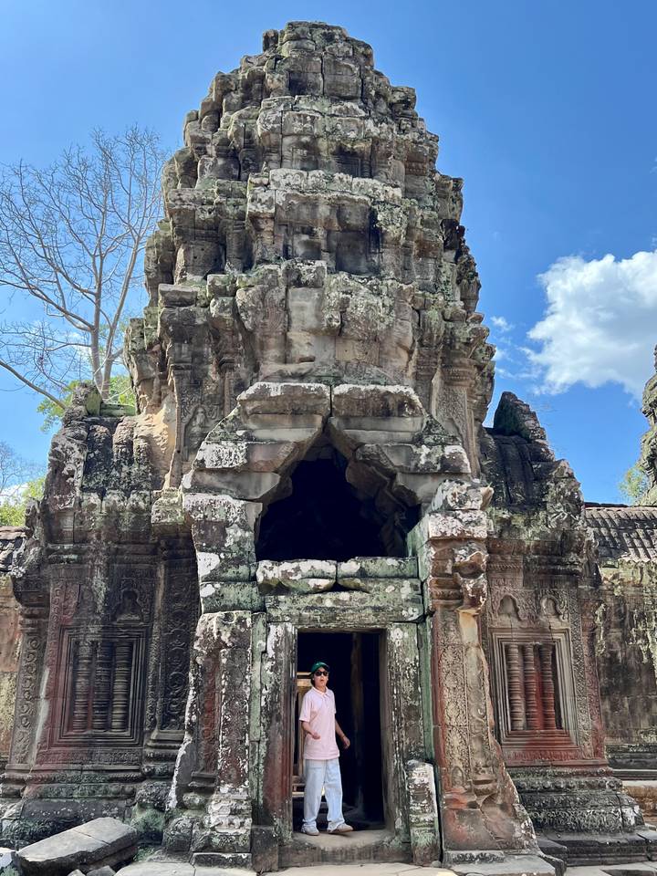 Ancient stone structure amidst lush greenery, with a bright blue sky.