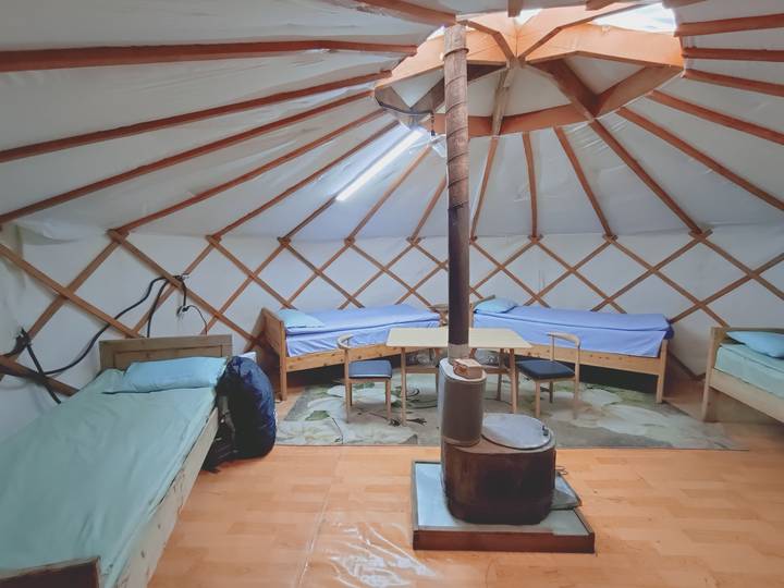 Interior of a yurt with wood furniture and stove.