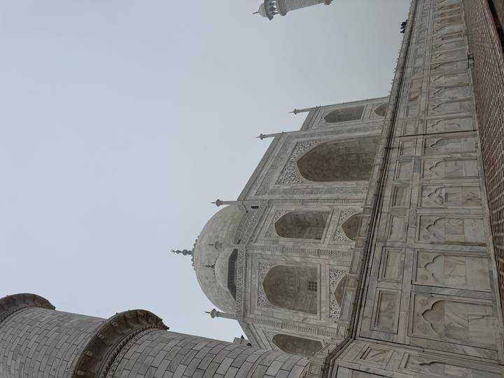 Marble façade and large dome of the Taj Mahal rising against a hazy sky