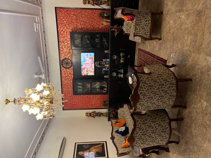 Elegant living room with chandelier, patterned armchairs and display cabinet in an Indian homestay.