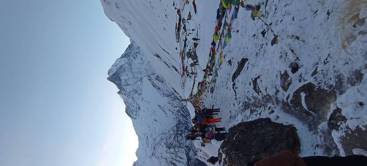 Trekkers approach a string of colourful prayer flags with Machhapuchhare towering behind.