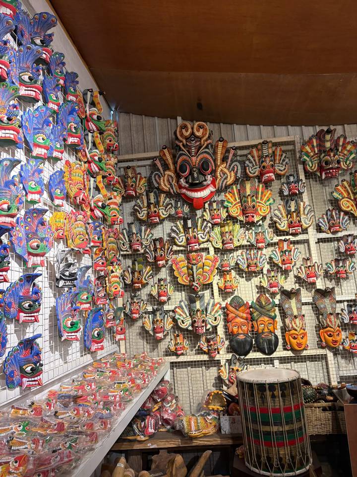 Wall covered with dozens of brightly painted Sri Lankan masks in varying sizes and designs.