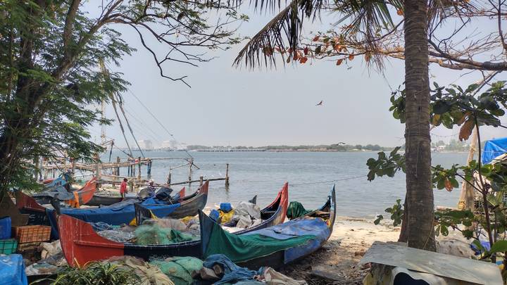 Colorful fishing boats and nets along a tropical shoreline with distant Chinese fishing nets.