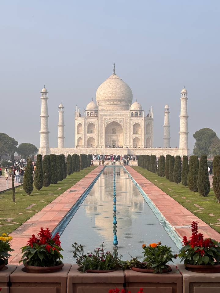 The iconic frontal reflection view of the Taj Mahal with crowds lining the pools and pathways.