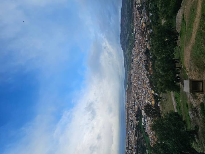 Elevated view of the sprawling city of Fes stretching beneath a bright blue sky.