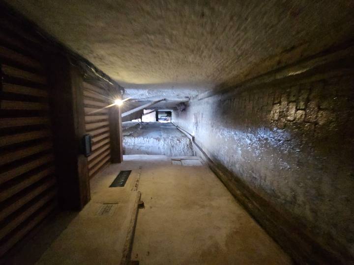 Dim, narrow medina passage with wet cobblestones and a single ceiling light.