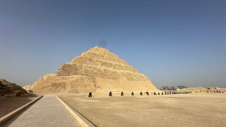 The Step Pyramid of Djoser rises in distinctive tiers against a cloudless desert sky at Saqqara.