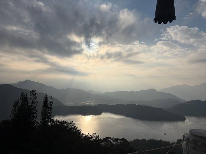 Soft morning light breaks through clouds over misty mountains and Sun Moon Lake.
