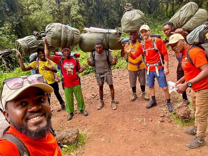 Smiling trekking team with heavy packs posing on a forested trail