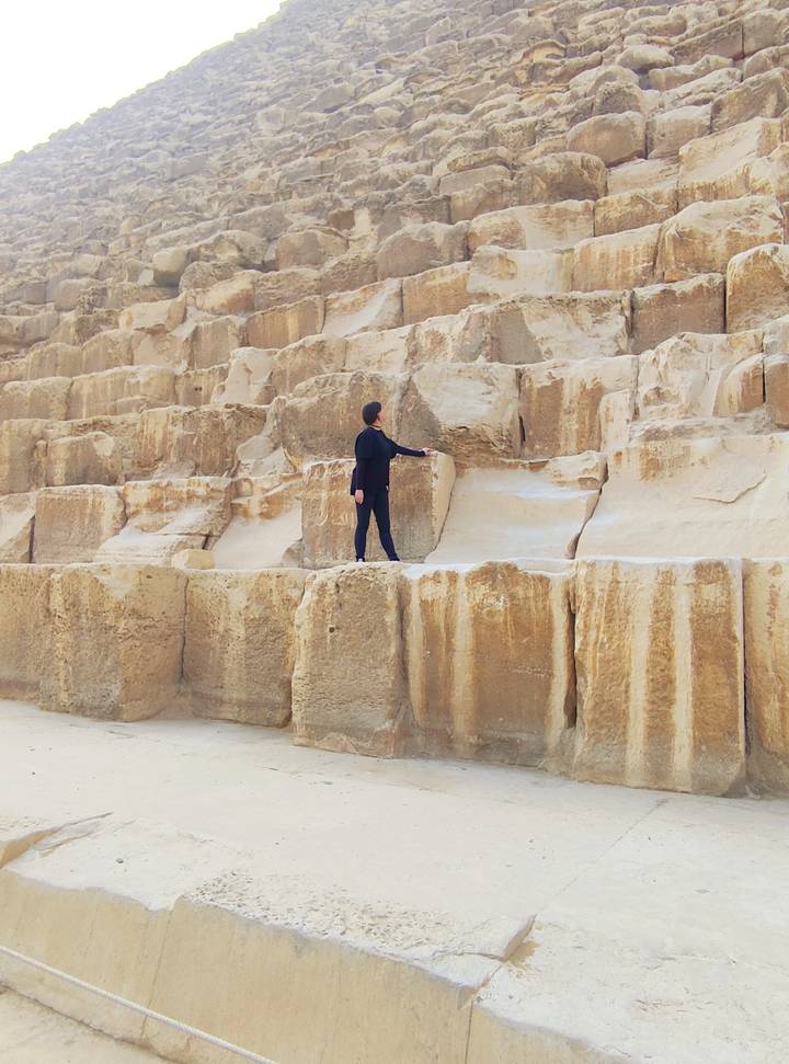 Solo traveler standing on the massive stone blocks of the Great Pyramid of Giza.
