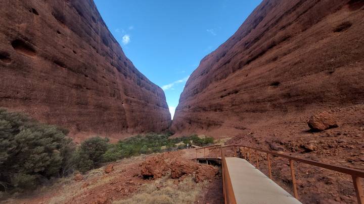 Wooden walkway through a dramatic narrow gorge between towering red rock walls in Kata Tjuta