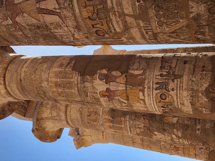 Painted hieroglyphic reliefs on massive stone columns inside Karnak Temple.