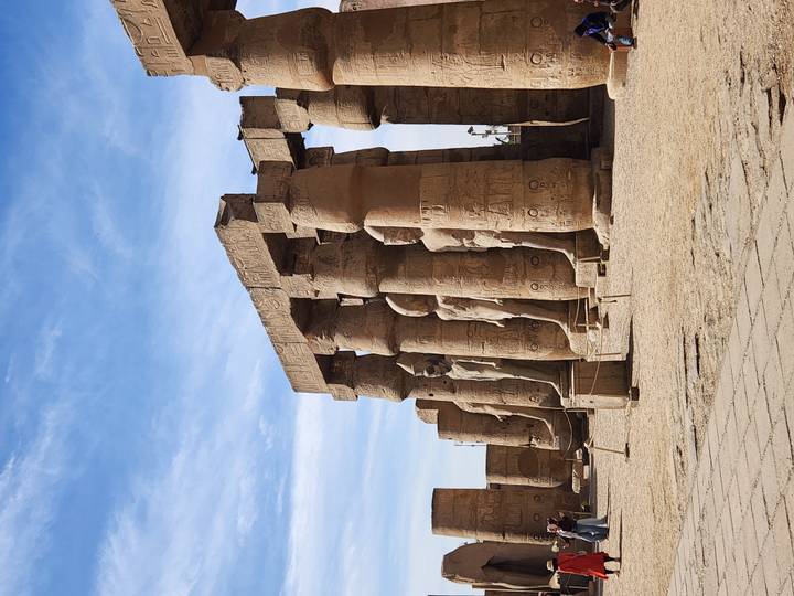 Row of towering sandstone columns with pharaonic statues in Luxor Temple courtyard.