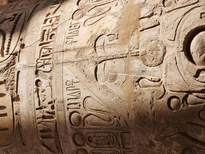 Close-up of intricate hieroglyph carvings and symbols on an ancient column.
