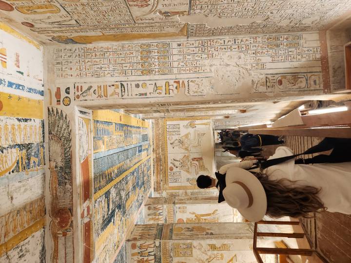 Visitors walk through a vividly painted tomb corridor in the Valley of the Kings.