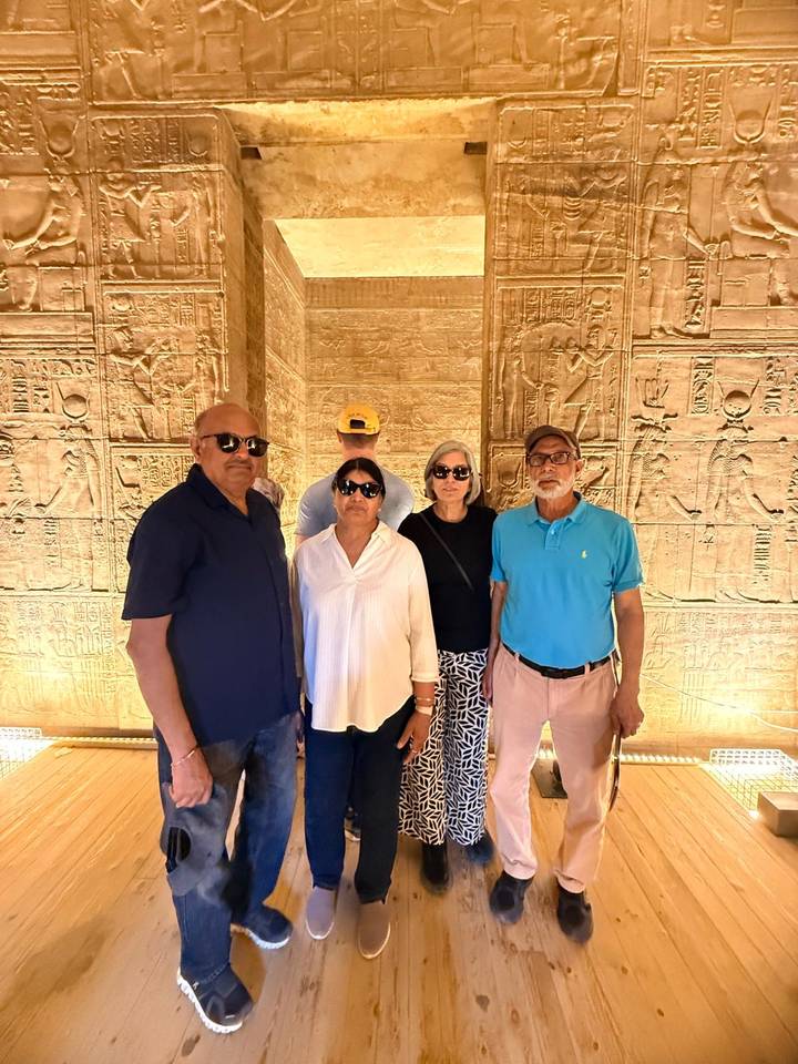 Travelers stand inside a hieroglyph-covered chamber illuminated with warm lighting.