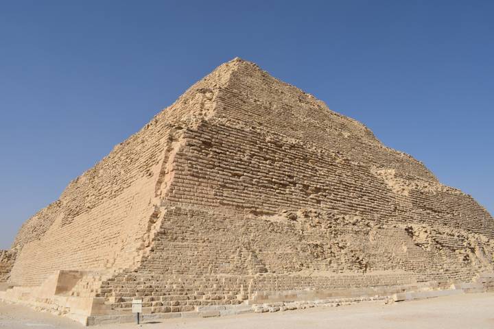 Stepped Pyramid of Djoser rising from the desert under a clear blue sky.