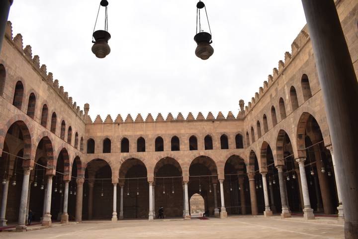 Interior courtyard of a historic Cairo mosque with symmetrical arches.