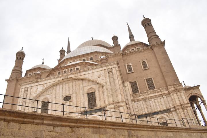 Low-angle view of Muhammad Ali Mosque’s domes and minarets against an overcast sky.