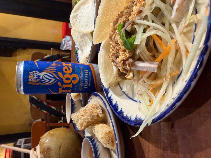 Vietnamese meal with Tiger lager, salad, and fried rolls on traditional ceramic plates.