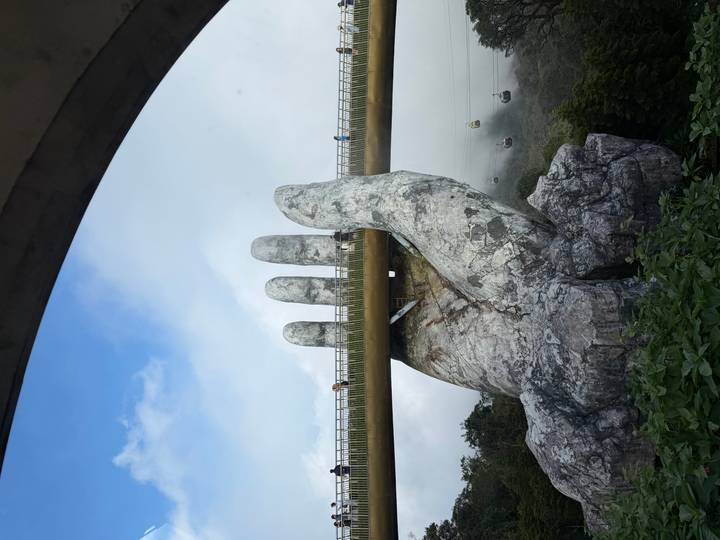 Daytime view of Da Nang’s Golden Bridge with cable cars in the misty valley below.