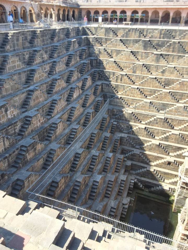 Geometric maze of stone steps at Chand Baori stepwell with dramatic shadows on the walls.