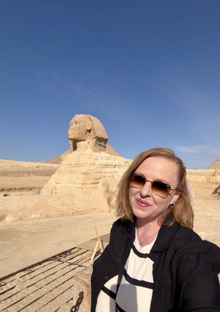 Woman takes selfie smiling in front of the Sphinx on a bright day