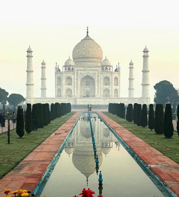 Iconic symmetrical view of the Taj Mahal with reflection pool flanked by cypress trees