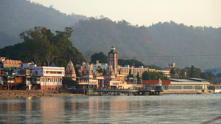 Haridwar riverside temples and clock tower glowing in late-afternoon light across the Ganges